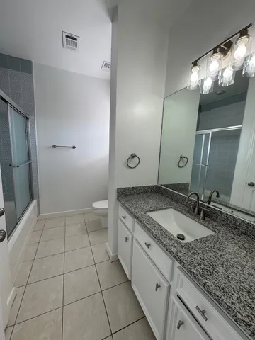 a bathroom with a granite countertop sink a toilet and a mirror