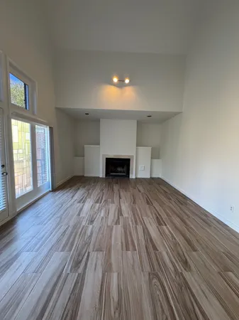 a view of empty room with wooden floor and fireplace