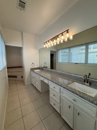 a spacious bathroom with a granite countertop sink a mirror and a vanity