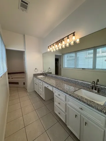 a spacious bathroom with a granite countertop sink a mirror and a vanity