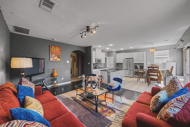 a living room with furniture kitchen view and a wooden floor