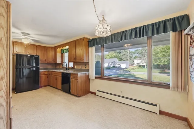 a kitchen with stainless steel appliances granite countertop a refrigerator a sink dishwasher a stove and a large window