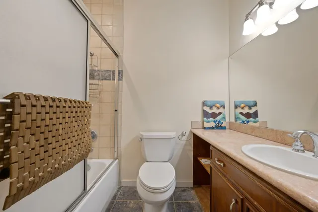 a bathroom with a granite countertop toilet a sink a mirror a bathtub and shower