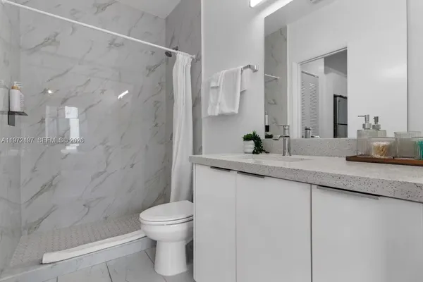 a bathroom with a granite countertop sink a toilet and a shower
