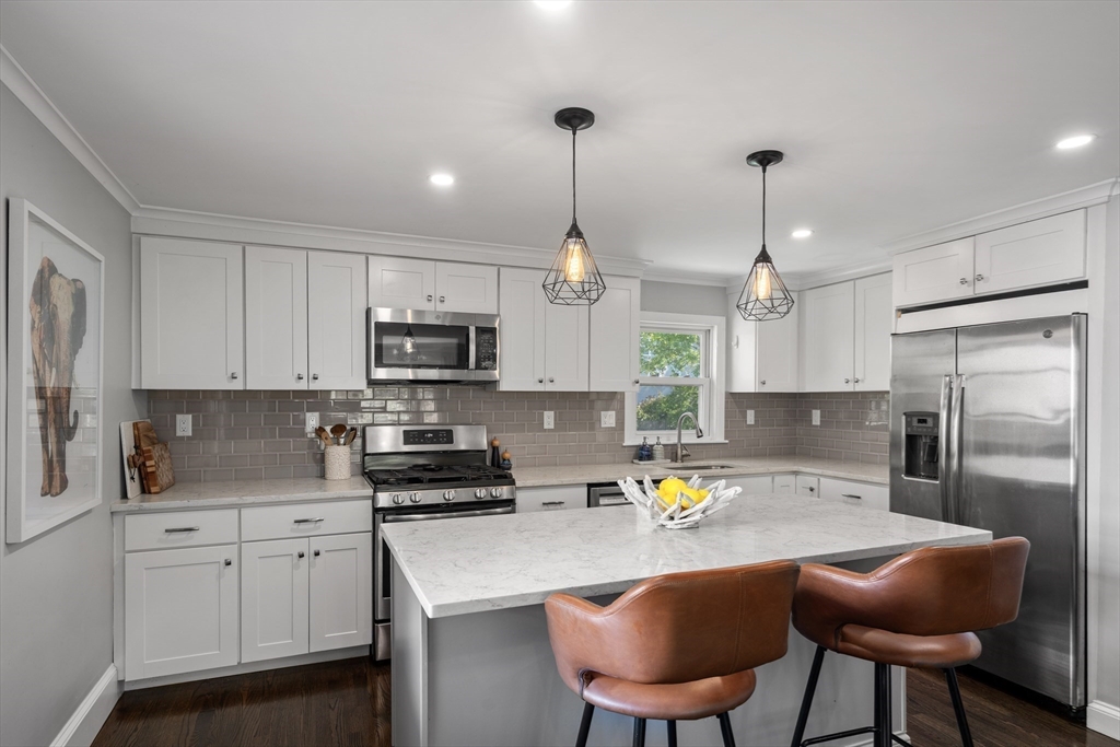 1 Dow Road Boston, MA 02132 - Photo 8 of 28 a kitchen with stainless steel appliances granite countertop a sink a stove a refrigerator cabinets and chairs