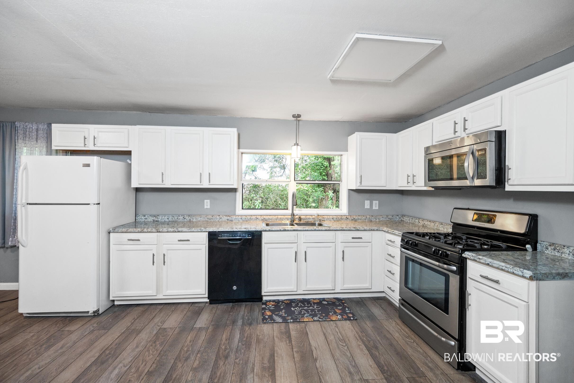 906 North Cedar Street Foley, AL 36535 - Photo 8 of 24 Kitchen featuring white cabinets, stainless steel appliances, dark wood-type flooring, and sink