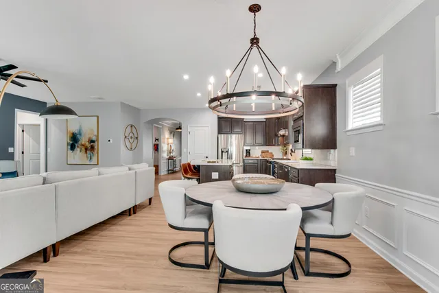 a dining room with wooden floor a chandelier a wooden table and chairs