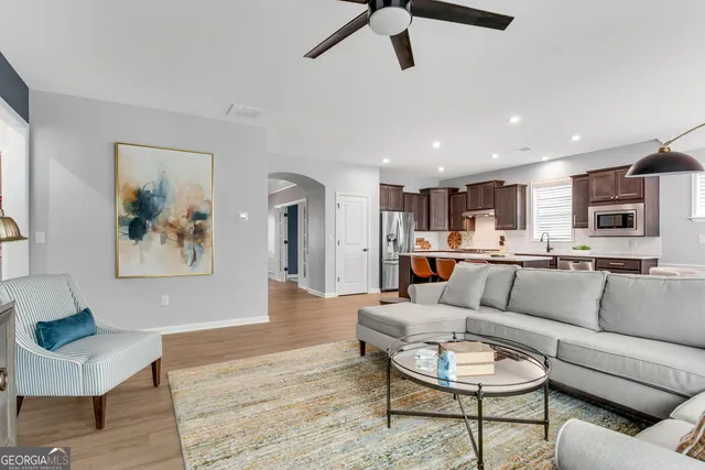 a living room with furniture kitchen view and a wooden floor