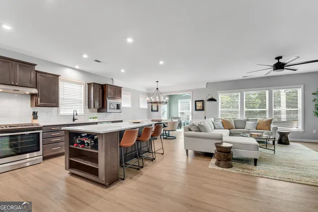 a living room with stainless steel appliances granite countertop a kitchen island hardwood floor and a living room