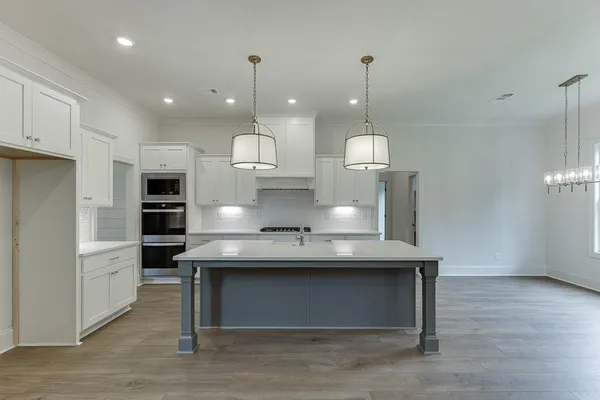 a kitchen with a stove a center island a sink cabinets and wooden floor