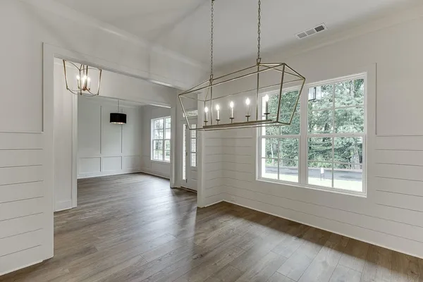 an empty room with wooden floor fireplace and windows