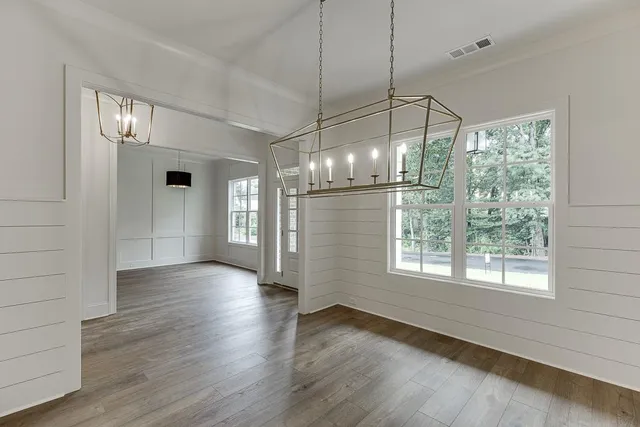 an empty room with wooden floor fireplace and windows