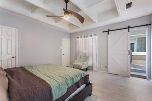 4050 Frankford Road, Unit 908 Dallas, TX 75287 - Photo 12 of 16 Tray ceiling with exposed beams, ceiling fan, wide plank wood-finish flooring, and a white barn door