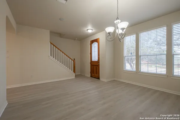 a view of an empty room with a window and wooden floor