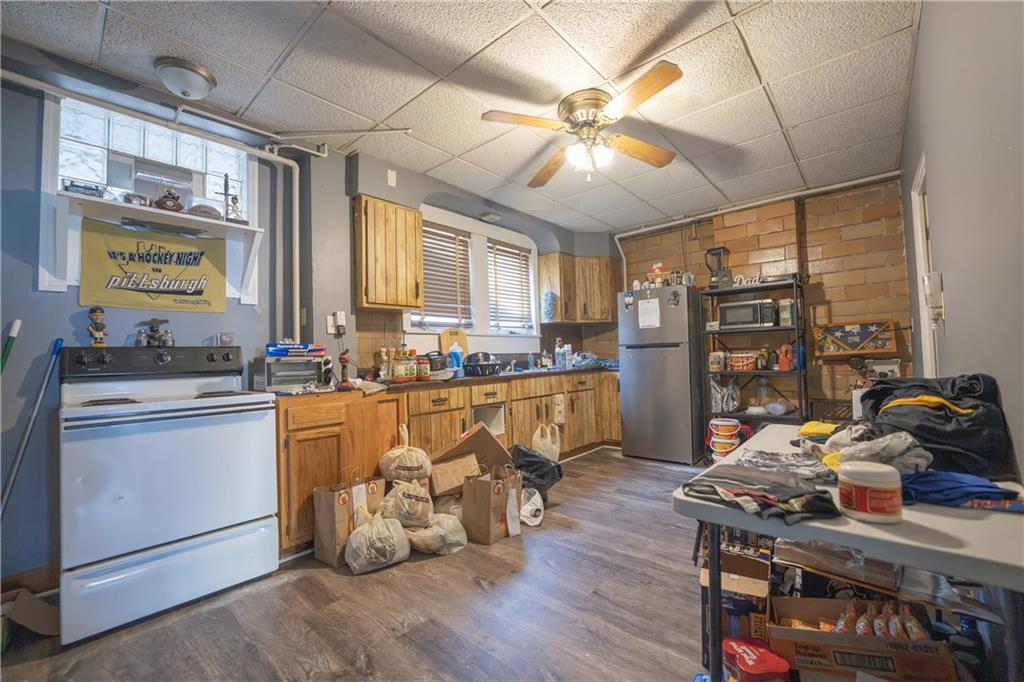 881 Lenz Avenue Ambridge, PA 15003 - Photo 6 of 30 a kitchen with stainless steel appliances granite countertop a stove top oven a refrigerator a dining table and chairs with wooden floor