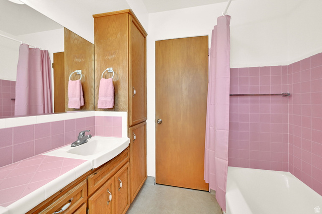 2467 South 2000 West Syracuse, UT 84075 - Photo 8 of 28 Bathroom featuring a built-in vanity with a pink tiled countertop, an integrated sink, and wood-finish cabinetry