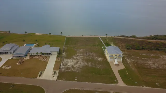 an aerial view of residential houses with outdoor space and ocean view