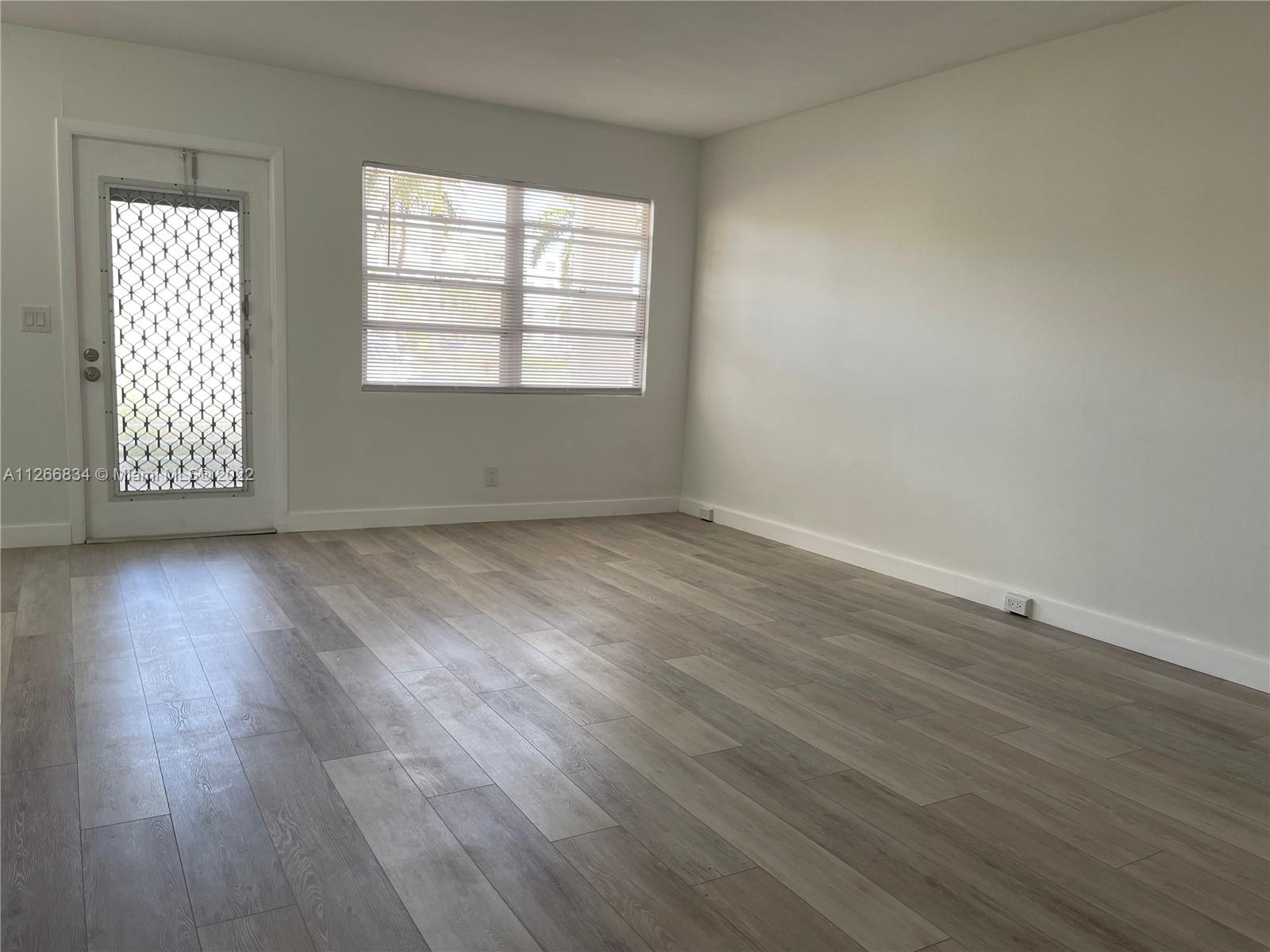1084 Guildford East Boca Raton, FL 33434 - Photo 12 of 34 an empty room with wooden floor and windows