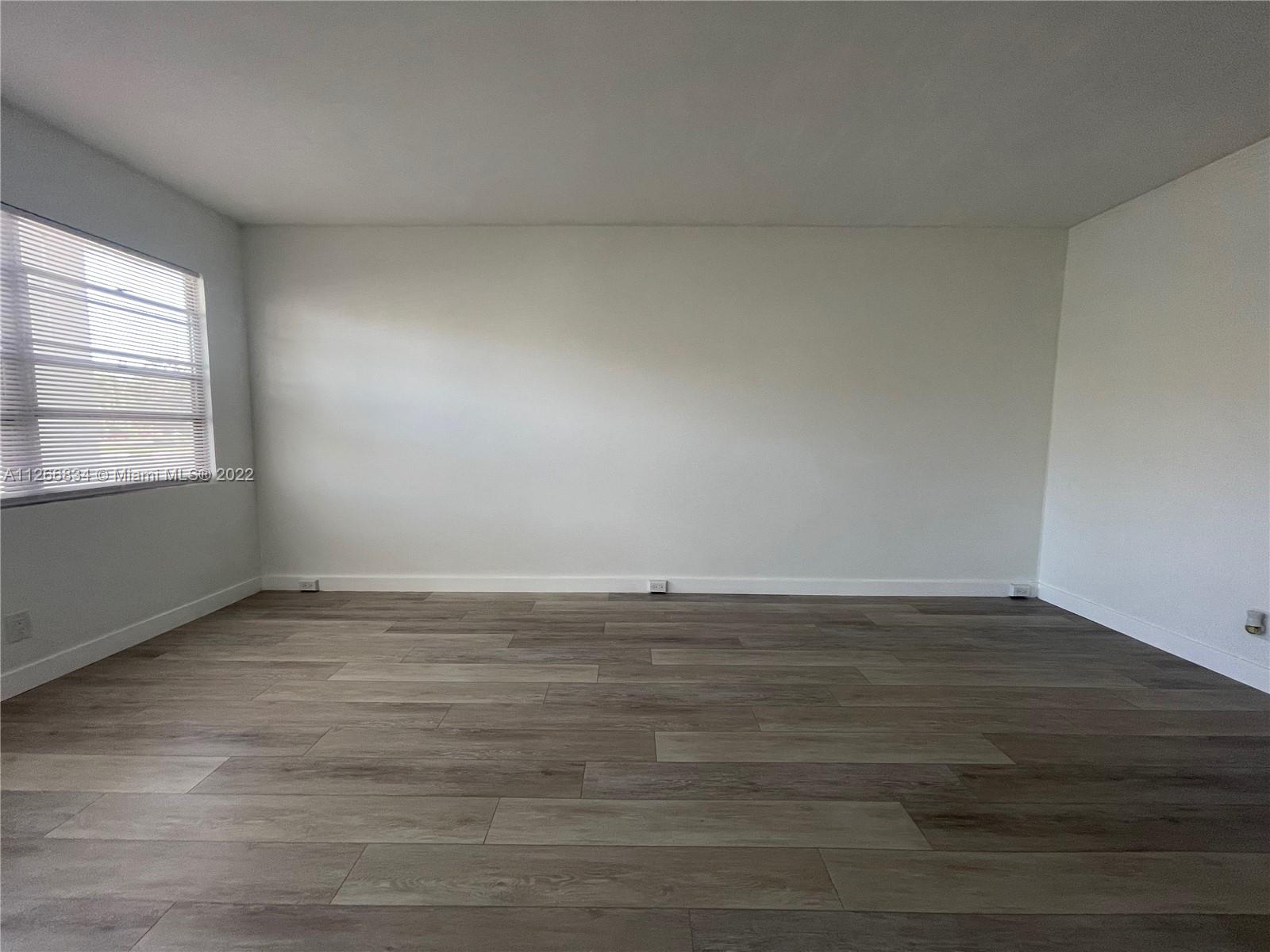 1084 Guildford East Boca Raton, FL 33434 - Photo 13 of 34 a view of an empty room with wooden floor and a window