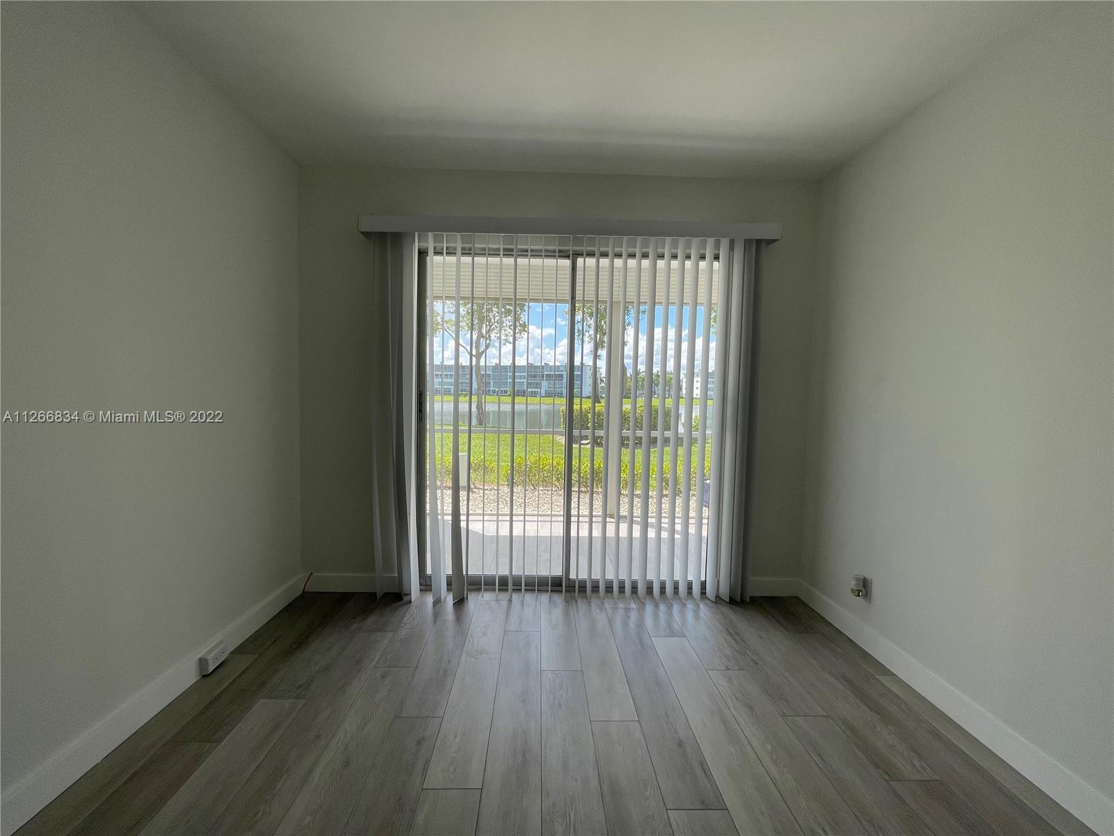1084 Guildford East Boca Raton, FL 33434 - Photo 22 of 34 an empty room with wooden floor and windows