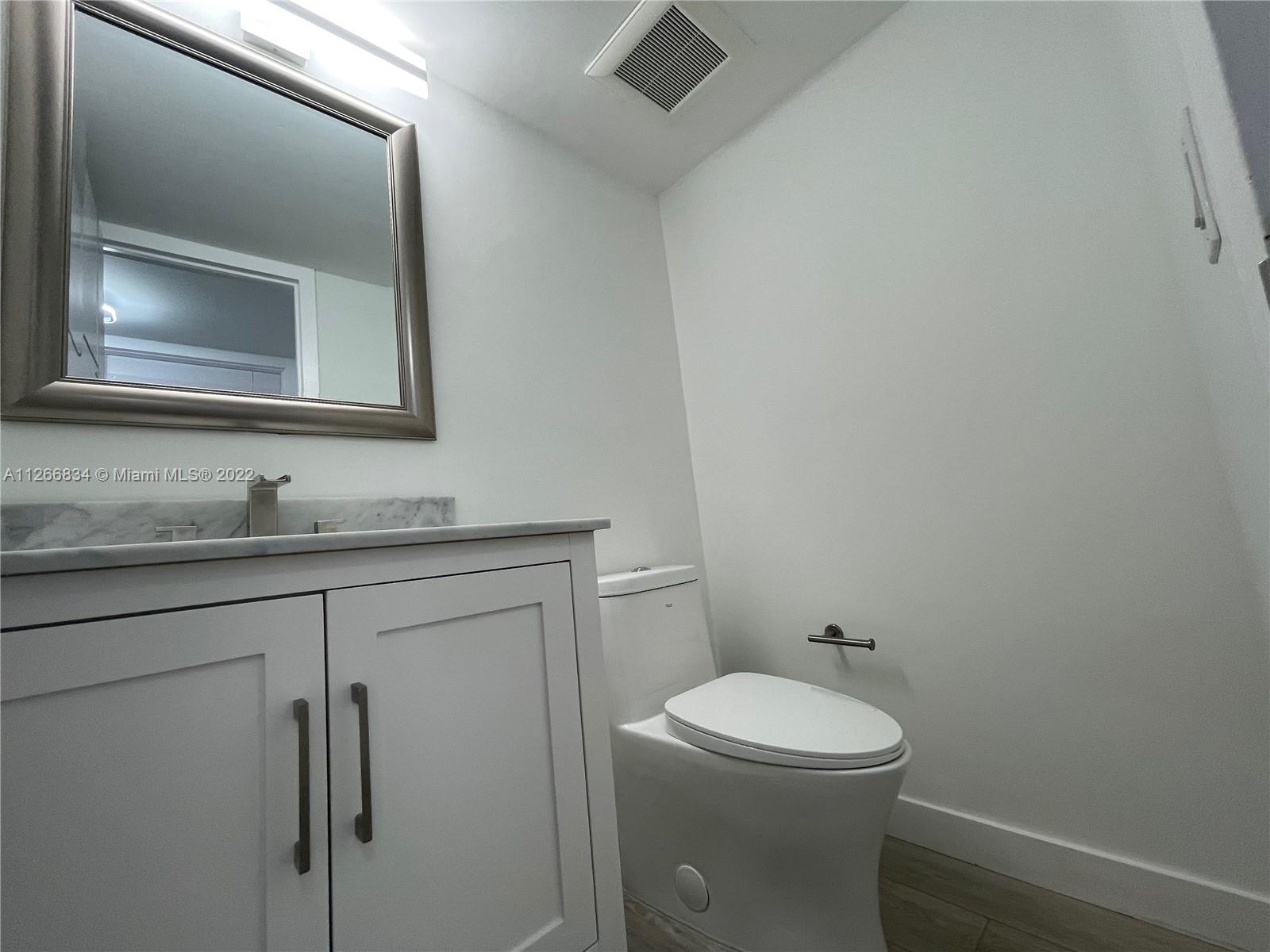1084 Guildford East Boca Raton, FL 33434 - Photo 25 of 34 a bathroom with a toilet sink and mirror