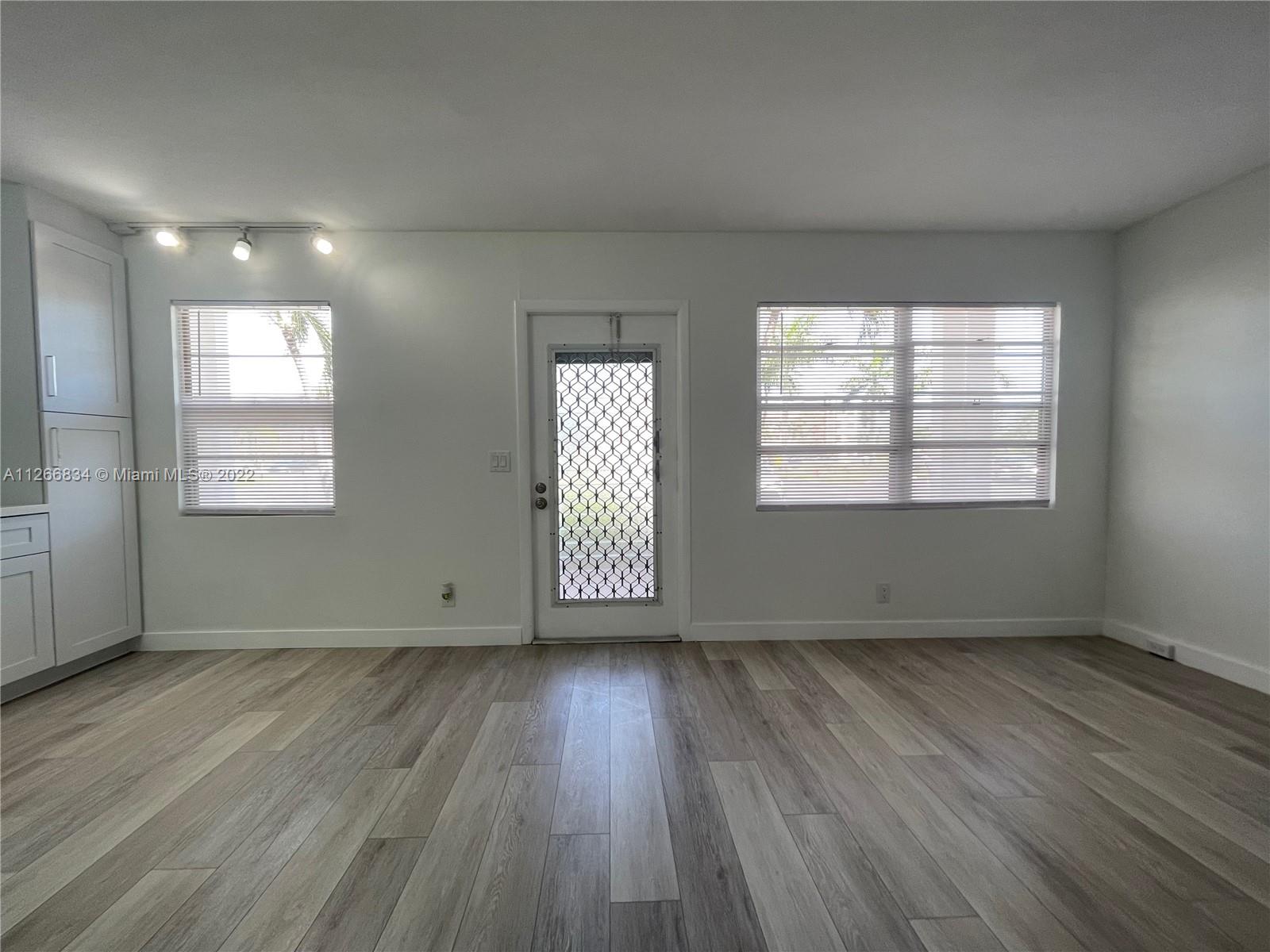 1084 Guildford East Boca Raton, FL 33434 - Photo 4 of 34 an empty room with wooden floor and windows