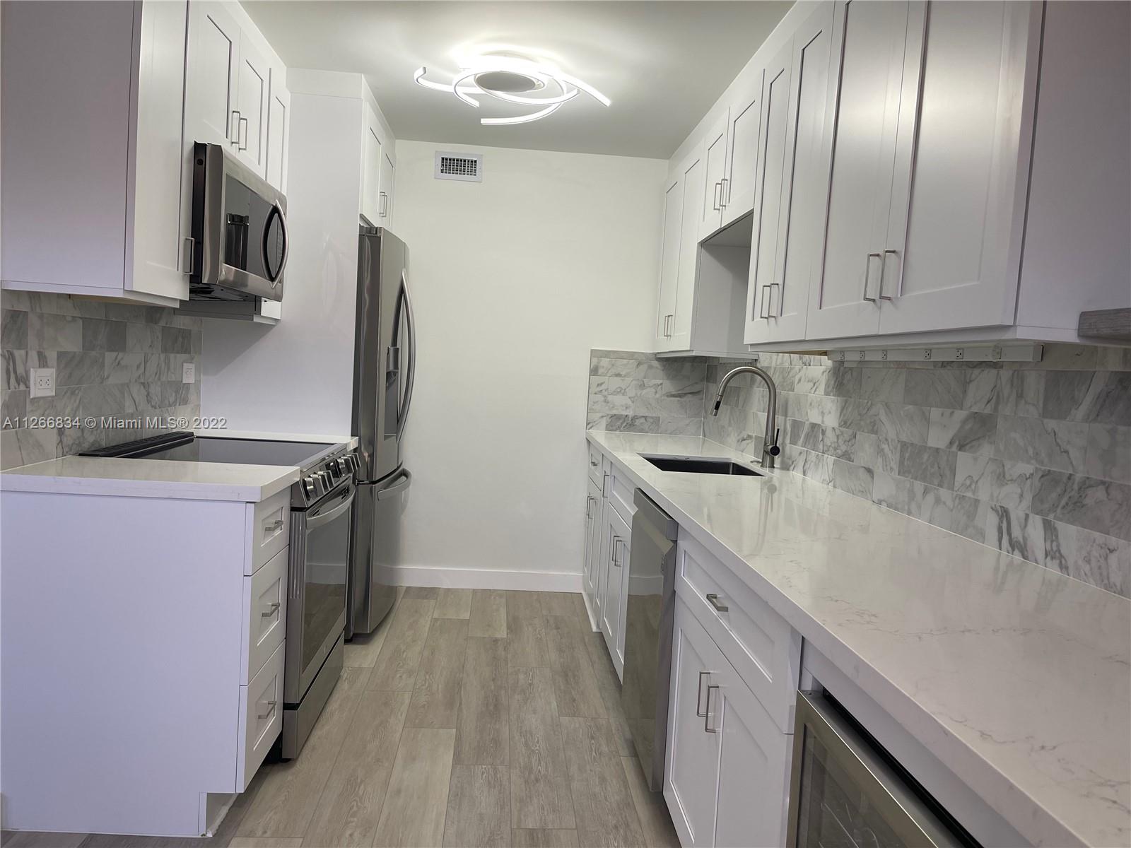 1084 Guildford East Boca Raton, FL 33434 - Photo 6 of 34 a kitchen with stainless steel appliances a sink stove and refrigerator
