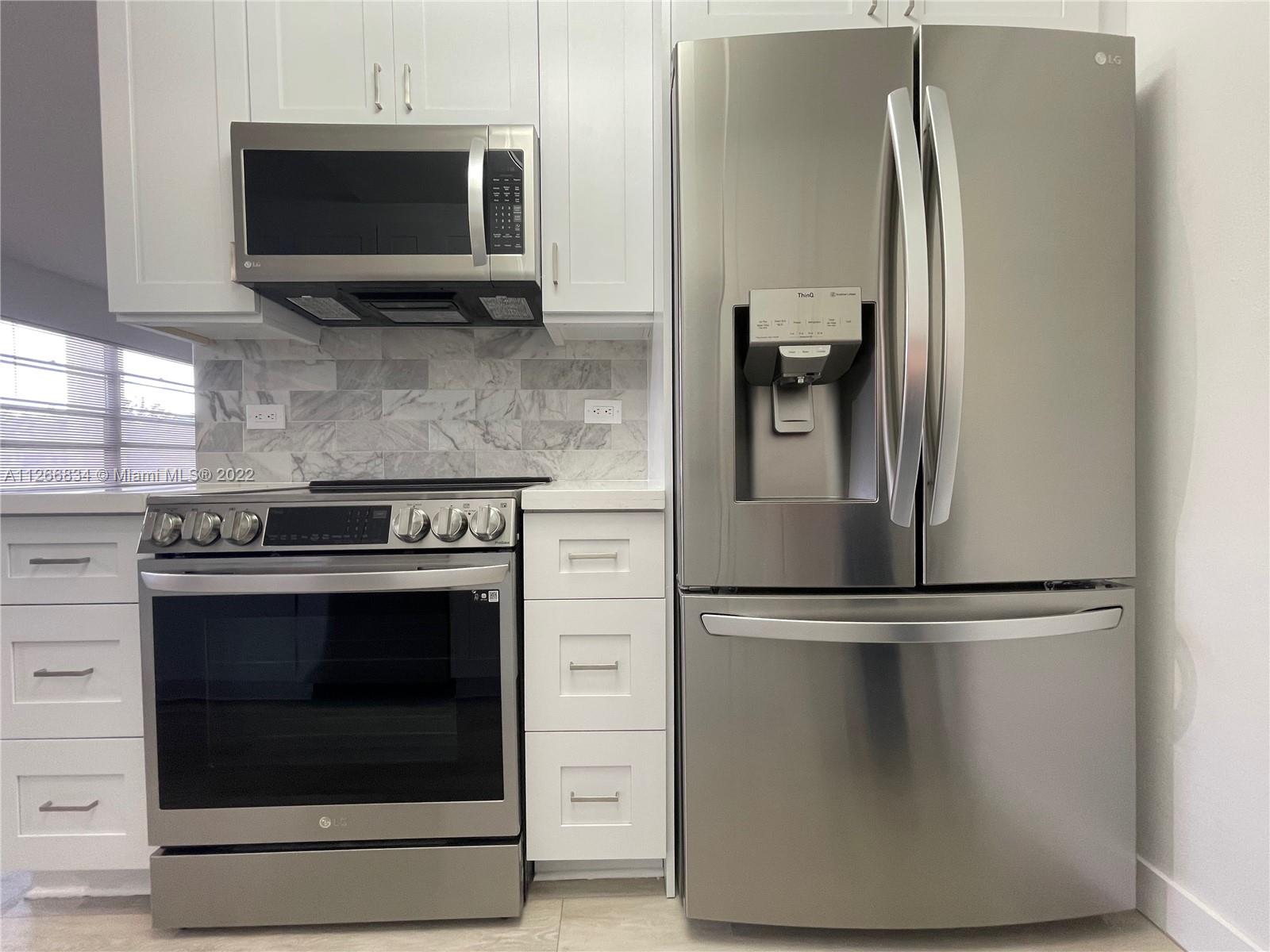 1084 Guildford East Boca Raton, FL 33434 - Photo 8 of 34 a kitchen with stainless steel appliances wooden cabinets and a stove