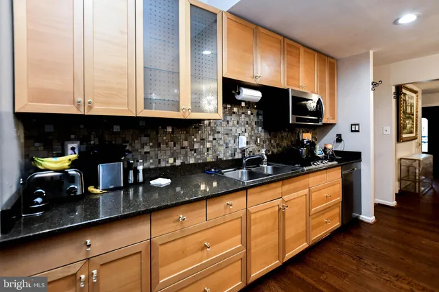 a kitchen with stainless steel appliances granite countertop a sink a stove and a wooden cabinets