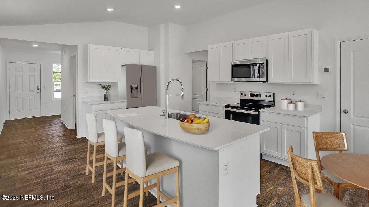 1 Divot Place Bunnell, FL 32110 - Photo 7 of 57 a kitchen with stainless steel appliances kitchen island granite countertop a table chairs microwave and sink