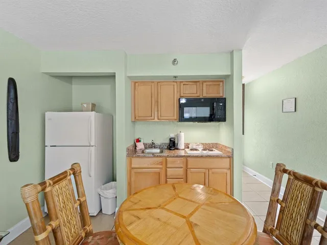 a kitchen with stainless steel appliances a sink a stove a refrigerator cabinets and dining table