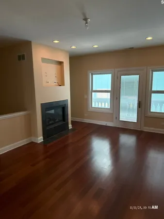 an empty room with wooden floor fireplace and windows