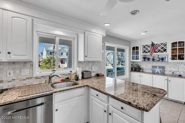 a kitchen with granite countertop a sink a stove and cabinets