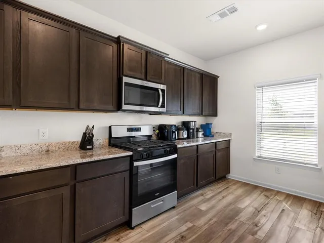 a kitchen with stainless steel appliances granite countertop a stove a sink and a microwave