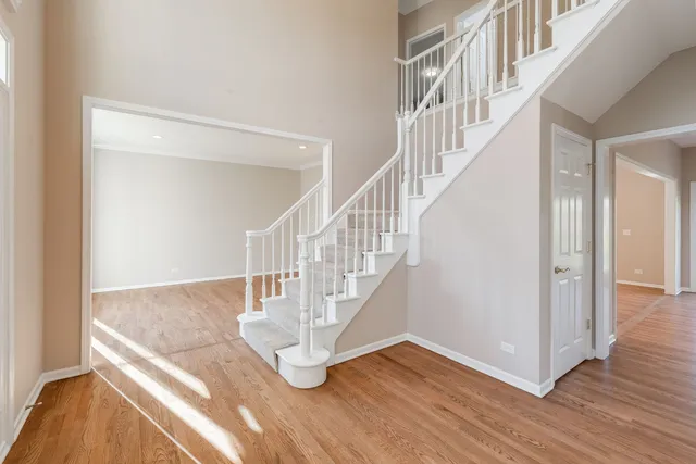 a view of an empty room with wooden floor fridge and a chandelier