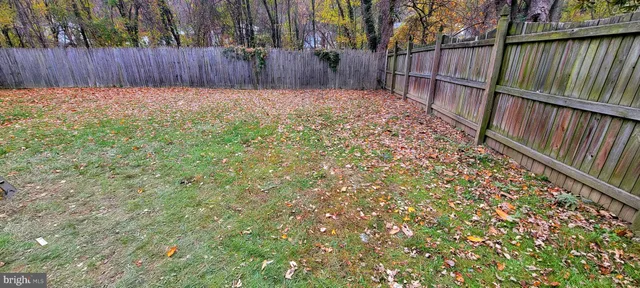 a view of backyard with wooden fence and large trees
