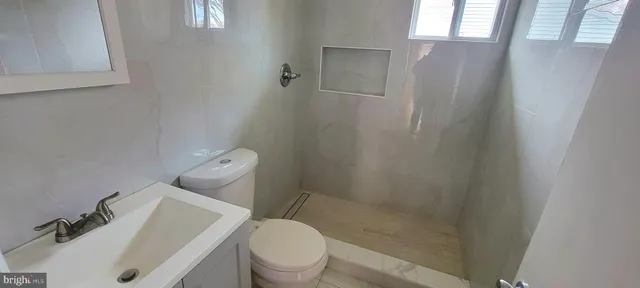 a white toilet sitting next to a bathroom sink and vanity
