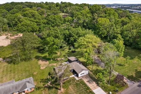 an aerial view of residential house with outdoor space and trees all around