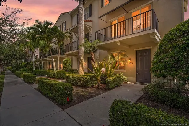 a view of a house with a small yard plants and large tree