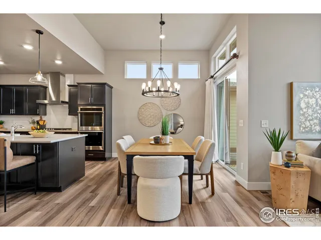a dining room with kitchen island a dining table wooden floor and a chandelier