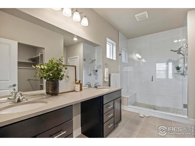 a bathroom with a sink double vanity granite tub shower and a mirror