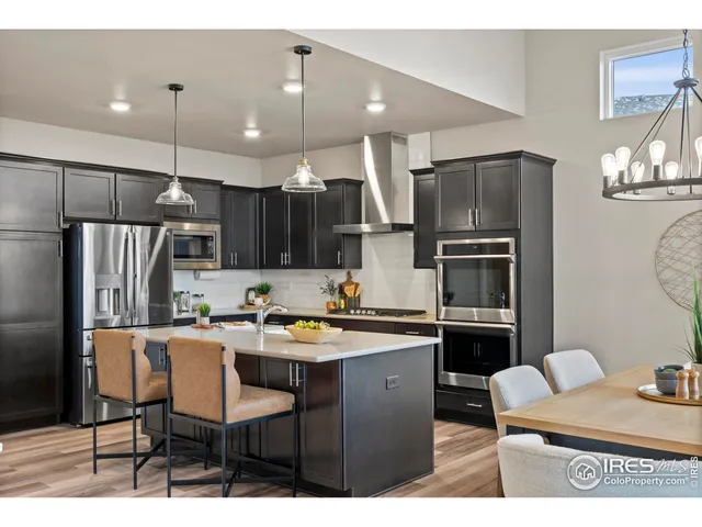 a kitchen with stainless steel appliances kitchen island granite countertop a table chairs and a refrigerator