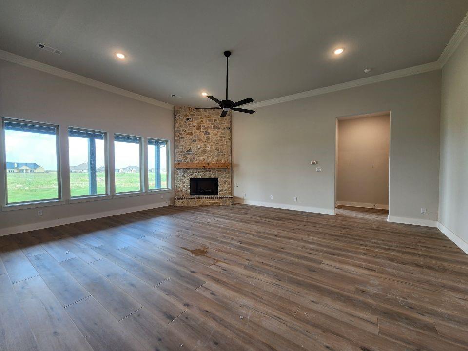 2305 Gypsum Street Krum, TX 76249 - Photo 14 of 22 Spacious living area featuring a stone fireplace with a wood mantle, wood-finish flooring, a contemporary ceiling fan, and multiple windows