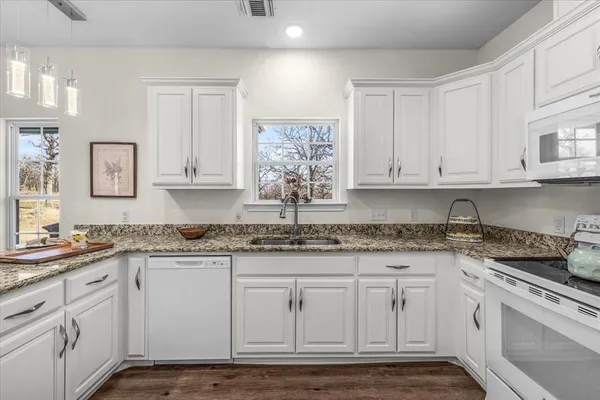 a kitchen with granite countertop white cabinets white appliances and sink