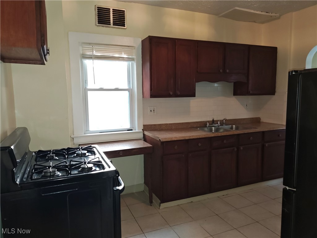 5213 Reed Avenue Ashtabula, OH 44004 - Photo 11 of 35 Kitchen with black appliances, decorative backsplash, and light tile patterned floors