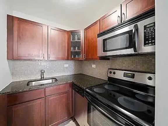 a kitchen with stainless steel appliances granite countertop a stove microwave and sink