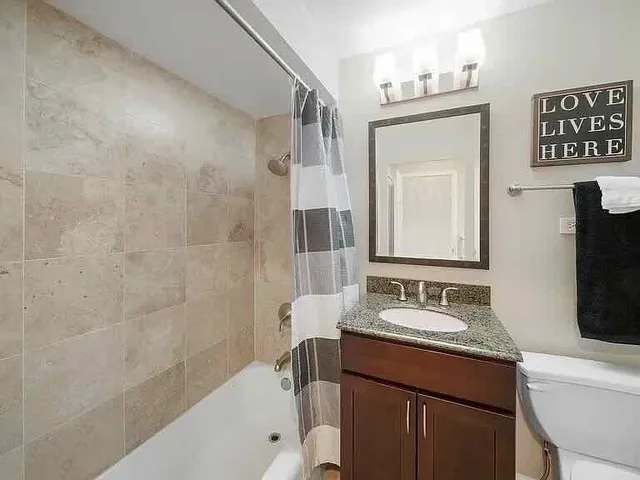 a bathroom with a granite countertop sink a mirror a vanity and a bathtub