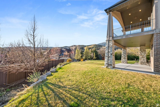 1205 North Elk Rdg Lane, Unit 202 Alpine, UT 84004 - Photo 72 of 88 Expansive backyard featuring a manicured lawn, brown privacy fencing, and a stone-clad covered patio