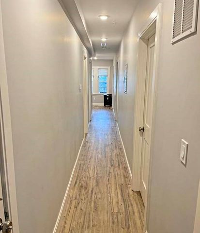 a view of a hallway with wooden floor and a bathroom