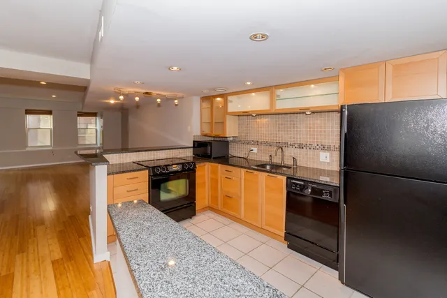 a kitchen with stainless steel appliances granite countertop a refrigerator a stove and a sink